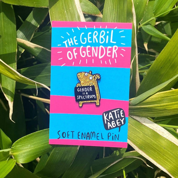 Gender Gerbil Enamel Pin, featuring a happy yellow glittery gerbil, holding a black sign which reads 'gender is a spectrum'. 35mm with rubber clasp. Designed by Katie Abey in the UK