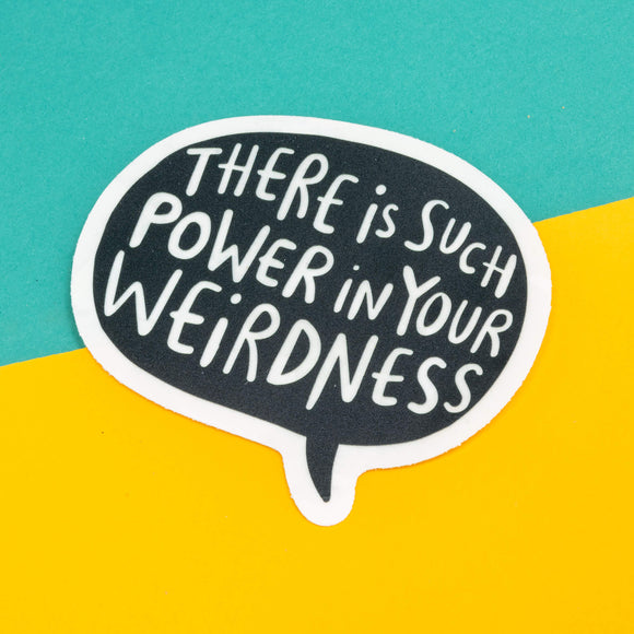 A window sticker shaped like a speech bubble stuck to a window that says there is such power in your weirdness. It is a black base and casts rainbows on a room. Designed By Katie Abey