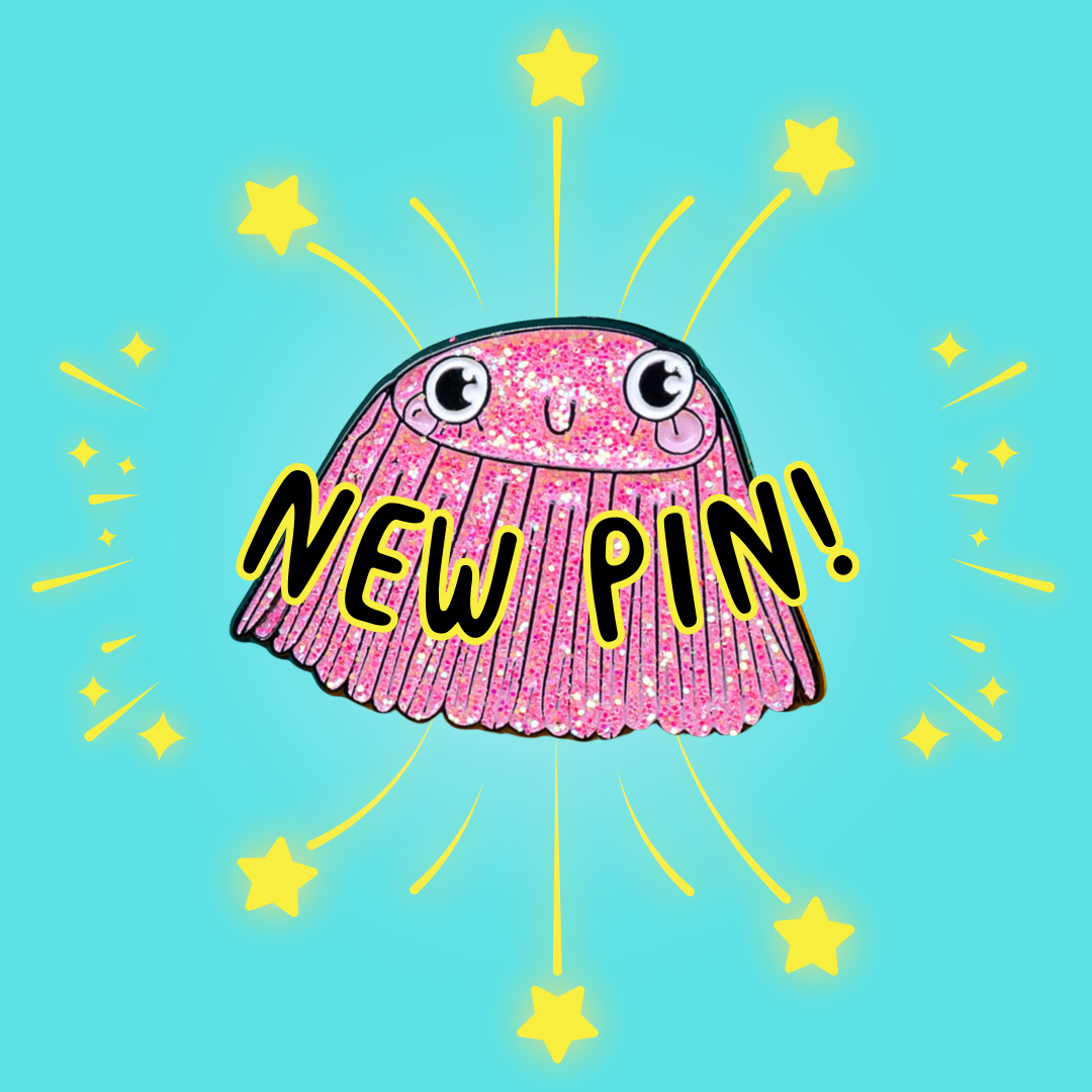 The Barnacle of Self Belief Enamel Pin Badge on a yellow and teal blue background. A pink glittering smiling barnacle pin with big eyes, eyelashes and pink cheeks all with a black outline. Hand drawn design by Katie Abey.