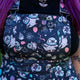 Close up of the Rebel Romance Ghost Party Flared Pinafore Dress showing the bib pocket, adjustable metal buckles and playful ghost print with balloons, stars and streamers. The dark cotton fabric features pastel pink, blue and lilac details for a fun alternative fashion look.
