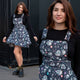 Model wearing the Rebel Romance Ghost Party Flared Pinafore Dress with a fun ghost print featuring balloons, streamers and stars. The close up highlights the adjustable buckle straps, bib pocket and fitted bodice, while the full length image showcases the flattering flared skirt and alternative styling with chunky boots.