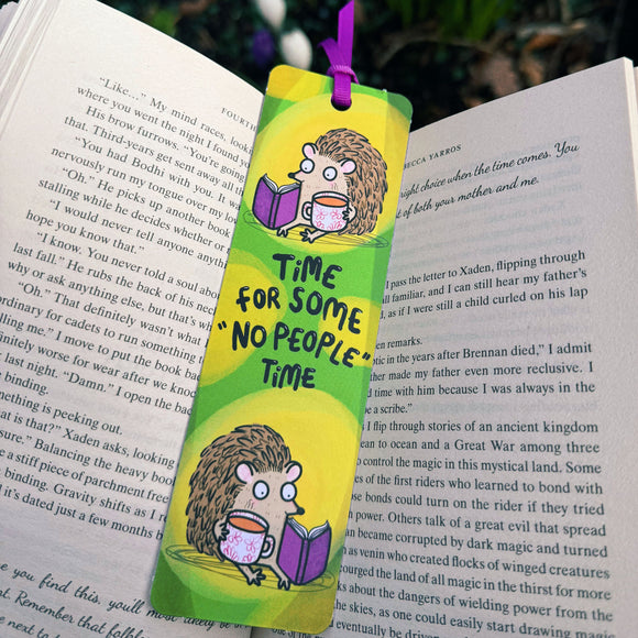 Time For Some No People Time Hedgehog Bookmark by Katie Abey placed inside an open book. Bright green and yellow striped background with illustrated hedgehog reading a purple book and holding a floral mug. Purple ribbon tie at the top. Funny introvert bookmark gift for book lovers and fans of quirky illustrated stationery.
