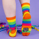socks in rainbow colours designed by Katie Abey featuring a green cat holding a sign saying 'cock womble' on the front