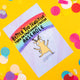 A light lilac postcard with a rainbow background with an illustration of a deer on it with an arrow pointing saying, 'the deer of feels'. Text above reads 'BETTER TOO SENSITIVE THAN AN EMOTIONALLY STUNTED ARSEHOLE' the card is on a yellow background with confetti around it