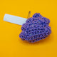 Handmade purple crochet plush toy shaped like a quirky poo character, made with sparkly vegan yarn and stuffed to hold its shape. The Galactic Poo Crochet Pal is inspired by Katie Abey’s illustration and created in collaboration with Forest Folk Crochet. A small cute novelty plush gift with a funny alternative aesthetic on a bright yellow background.