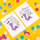Two postcards next to each other featuring the empathic eel one they are empowered and the other 'not so great' the eel is purple and drawn by Katie Abey. It is shot on a yellow background.