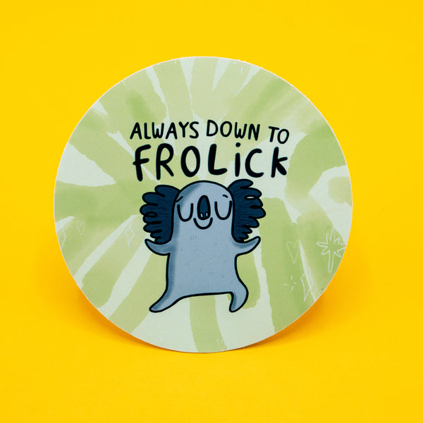 Round vinyl sticker featuring a happy cartoon koala with arms outstretched and eyes closed, dancing beneath the hand-lettered phrase “Always Down to Frolick.” The background is a soft green tie-dye pattern with subtle sparkles and doodles. Approx. 8cm in diameter. A playful, feel-good design by Katie Abey that celebrates joyful weirdness and spontaneous fun.