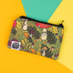 This Katie Abey coin purse features her illustrated mushroom characters, set against a vibrant forest-inspired backdrop of toadstools, acorns, and autumn leaves. Perfect for keeping your coins or small items safe while showing off your love for quirky accessories. The green-toned design is ideal for fans of weird and wonderful patterns, and the purse is finished with a collaborative tag from Katie Abey x Dawny's Sewing Room, showcasing its handmade charm.