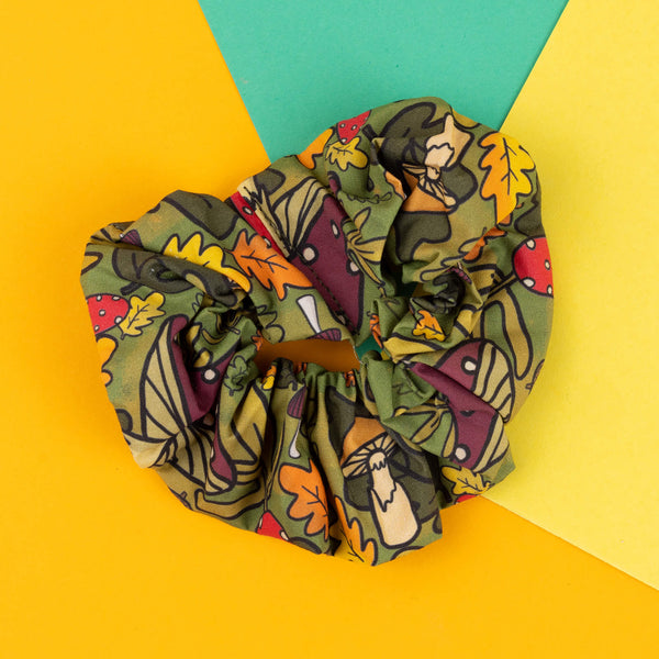 Katie Abey’s quirky handmade scrunchie features a whimsical mushroom and forest design, perfect for adding a touch of nature to your everyday look. With toadstools, acorns, and autumn leaves in the pattern, it’s a playful accessory for anyone who loves quirky designs. The green and earthy tones of the print make it an ideal choice for those who want to stand out and embrace their weirdness. Great for everyday use or gifting to a friend who loves fun accessories.