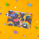 Katie Abey x Dawny's Sewing Room pouch featuring a rainbow animal print on a black background, adorned with quirky illustrations like a unicorn, fox, and kangaroo. The pouch has a white zip closure and fun, vibrant characters scattered across the design, making it perfect for playful storage of essentials. Photographed on a yellow background with colourful pom-poms to enhance the vibrant, whimsical aesthetic.