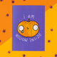 A whimsical Halloween-themed postcard by Katie Abey featuring a sad, cartoonish pumpkin with large, round eyes and a tear falling down its face. The pumpkin has the phrase "I am hollow inside" written around it in white text on a vibrant purple background. The card is placed on a bright orange surface decorated with small purple spider confetti, giving off playful, spooky vibes. Katie Abey is an illustrator and small business that encourages people to embrace their weirdness.