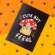 Katie Abey's 'Cute but Feral' postcard shows a fun cartoon cat under a red and white mushroom hat with a quirky, wide-eyed look. Encouraging individuality and weirdness, this playful design pops against an orange background with scattered purple spiders. Perfect for adding a touch of spooky fun to gifts or home decor. Created by Katie Abey, an illustrator and small business that celebrates being different and unique.