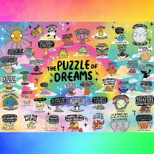 A vibrant, rainbow-themed illustration titled "The Puzzle of Dreams" by Katie Abey, featuring whimsical characters and motivational phrases like "Have the audacity," "You are here to shine," and "Take the time to recalibrate your energy." The artwork is filled with uplifting, quirky messages and cute animals like pandas, snails, and cats, encouraging self-love and positivity. Perfect for puzzle fans who enjoy colourful, inspiring designs with a sprinkle of weirdness.