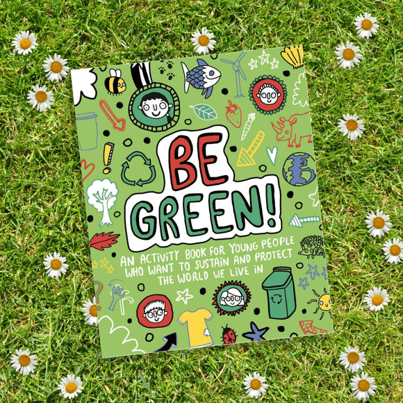 The Be Green Activity Book illustrated by Katie Abey. The book is laid on the grass amongst daisies. The front cover of the book is green with various illustrations of people, animals, symbols, clothes and environmental themes. The text says Be Green! An activity book for young people who want to sustain and protect the world we live in.