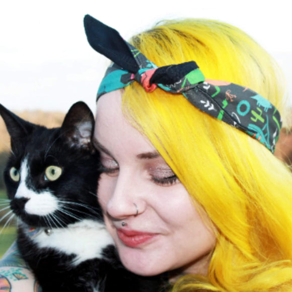 Katie Abey wearing the Jurassic Park Dinosaur Hair Tie with her black and white cat. 