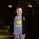 The sensitive sole t shirt worn by a chid smiling outside. The grey t shirt has an illustration of a yellow sole with tears from it's eyes with a rainbow above it with the text sensitive sole written in front. There is a speech bubble from the sole's mouth that reads feeling the feelings