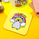 The Penguin of Procrastination Coaster. The coaster is a yellow background with a baby penguin holding its arms up with a rainbow and text behind it reading 'I have accomplished NOTHING'. There's an arrow pointing at the bottom of the penguin with text reading 'the penguin of procrastination'. Designed by Katie Abey in the UK.