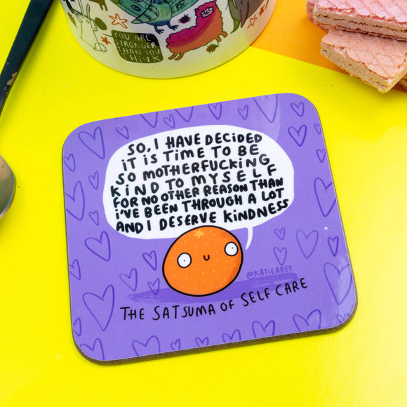 Satsuma of Self Care Coaster is a purple coaster with heart background and an illustrated satsuma smiling with a speech bubble saying 'So, Have decided it is time to be so motherfucking kind to myself for no other reason than I've been through a lot and I deserve Kindness.'