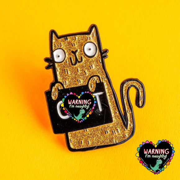 Gold glitter enamel pin of a quirky illustrated cat holding a black sign with bold white text, on a bright yellow background. Designed by Katie Abey, this humorous sweary cat pin badge features wide eyes and a playful expression, perfect for alternative fashion lovers and fans of cute but cheeky accessories.

