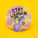 Round vinyl sticker featuring a quirky creature riding a pink unicorn with a rainbow mane, set against a dreamy pastel sky. The words “Stay Whimsical” are written above in bold black text. Approx. 8cm in diameter, this colourful, high-quality sticker is by Katie Abey, a small UK illustrator encouraging you to embrace your weirdness with fun and positivity.