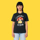 Model wearing the black Cute But Feral Cat adults t shirt. Front view showing cute illustrated cat artwork with mushroom hat and playful slogan. Unisex organic cotton t shirt styled casually against a yellow background.