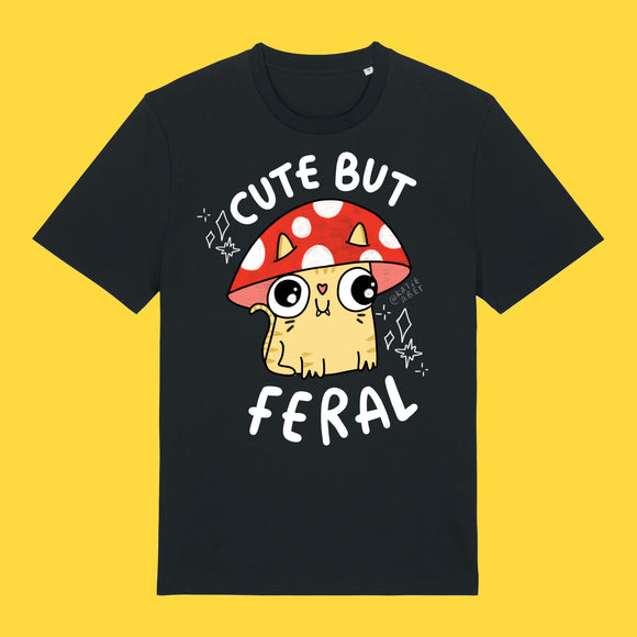 Black unisex adults t shirt featuring the Cute But Feral Cat artwork by Katie Abey. Illustrated cat wearing a red spotted mushroom hat with bold white Cute But Feral text. Quirky graphic tee for cat lovers and alternative fashion fans.

