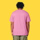 Model wearing the bubble pink Cute But Feral Cat adults t shirt shown from the back. Loose fitting organic cotton tee with a casual drape, styled with green cargo trousers on a yellow background.