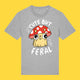 Heather grey unisex t shirt featuring the Cute But Feral Cat artwork by Katie Abey. Cartoon cat wearing a red spotted mushroom hat with bold white text reading Cute But Feral. Fun, quirky illustrated graphic tee for adults.