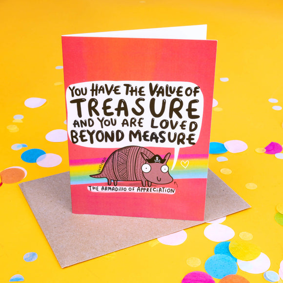 A pink greeting card with purple, yellow and blue stripes and a pink armadillo illustration with a little pirate hat on it's head with a speech bubble coming from it's mouth that reads 'you have the value of treasure and you are loved beyond measure. 'The Armadillo of Appreciation' is written under the illustration with an arrow pointing up towards it.