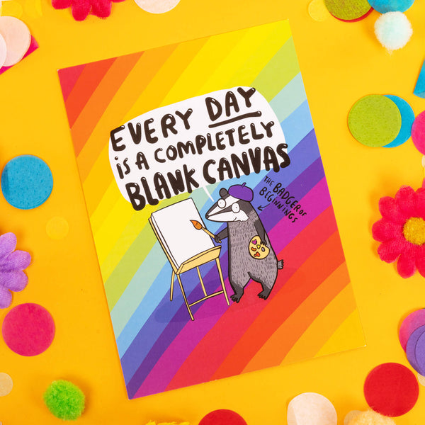 Fun A6 greeting postcard reading 'Every day is a completely blank canvas' and 'the badger of beginnings' in black text on a rainbow background, featuring happy badger illustration wearing a purple beret and painting onto an artists easel. Designed by Katie Abey in the UK.