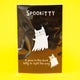 A Katie Abey Spookitty glow in the dark glitter enamel pin badge shown on its black backing card inside clear packaging against a bright yellow background. The ghost cat enamel pin has a white glitter finish and a bold black outline. Fun spooky themed accessory for bags, denim jackets, and pin collections.