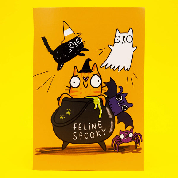 Bright orange A6 postcard featuring Katie Abey’s Feline Spooky Halloween Cats illustration. An orange witch cat sits in a bubbling cauldron marked Feline Spooky, surrounded by a black cat in a candy corn hat, a ghost cat, a bat and a purple spider. Printed on 350gsm silk card and perfect for Halloween gifting or decorating.