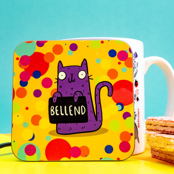 a coaster of a purple cat on a yellow confetti spotty background smiling holding a sign saying 'BELLEND'