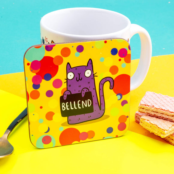 a coaster of a purple cat on a yellow confetti spotty background smiling holding a sign saying 'BELLEND'