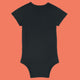 Black organic cotton baby bodysuit by Katie Abey shown from the back. Soft short sleeve babygrow with popper fastening and comfortable interlock cotton fabric. Stylish alternative baby clothing designed by a UK illustrator known for encouraging everyone to be proudly weird.
