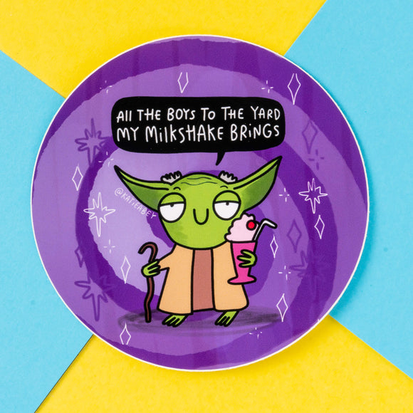 Circular sticker showcasing a green alien-inspired character holding a pink milkshake and a cane, with a speech bubble that reads, "All the boys to the yard my milkshake brings." This fun design by Katie Abey has a vibrant purple background with whimsical white star and diamond illustrations. Katie Abey is a British illustrator and small business that encourages everyone to embrace their weirdness and express themselves through humour and creativity.