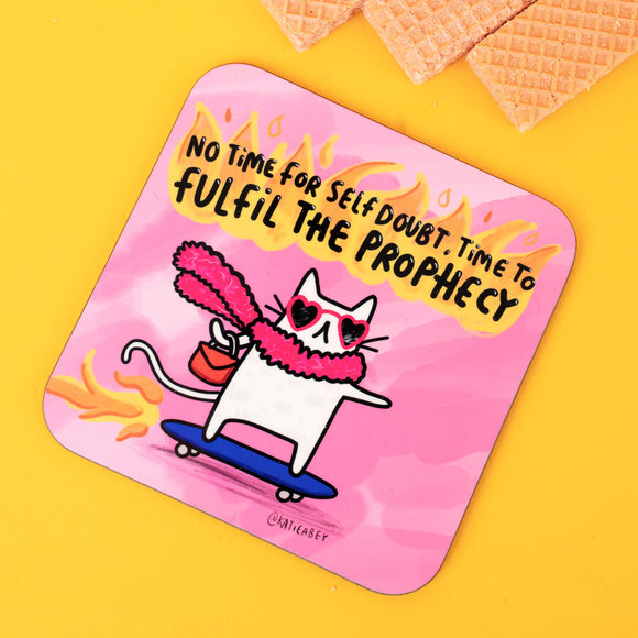 Katie Abey’s illustrated pink coaster with a sassy white cat wearing heart-shaped sunglasses, a pink scarf, and skateboarding with fiery flair. The text reads, "No time for self-doubt, time to fulfil the prophecy," blending humour with motivational vibes.