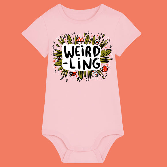Cotton pink organic cotton baby bodysuit featuring the “Weird-Ling” design by Katie Abey. Playful illustration with mushrooms, foliage and bold lettering celebrating being weird and wonderful. Short sleeve baby grow with shoulder snap fastening and bottom poppers, ideal for quirky baby gifts and alternative baby clothes.