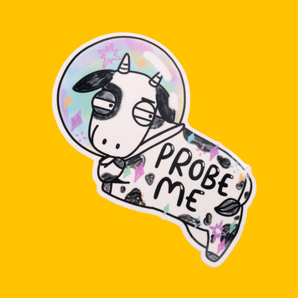 A sticker of a black and white cow in a rainbow-coloured space helmet, with the text "PROBE ME" on its body. The cow has a bored expression, and the background is bright yellow. This quirky design is from Katie Abey, a small colourful company for fun likeminded weirdos.