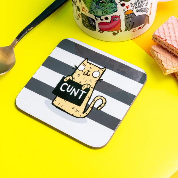 A very naughty swearing yellow cat holding a sign that says 'cunt' on a black and what striped background.