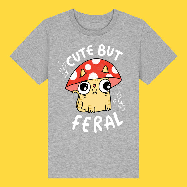 Front view of the Cute But Feral Cat Kids T Shirt by Katie Abey in heather grey. Kids organic cotton tee featuring a cute illustrated feral cat under a red spotted mushroom with the slogan Cute But Feral, photographed on a bright yellow background.
