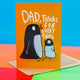 Dad, thanks for everything a6 greeting card stood up on the brown envelope it comes up, rainbow paper and marshmallows on a white background. The front cover is an orange background with an adult black penguin and baby grey penguin facing each other with text round them reading 'Dad, thanks for everything'. Designed by Katie Abey in the UK.
