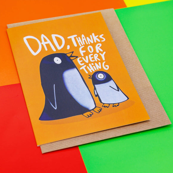 The card is orange with an adult black penguin and baby grey penguin facing each other with text round them reading Dad thanks for everything. Designed by Katie Abey in the UK.