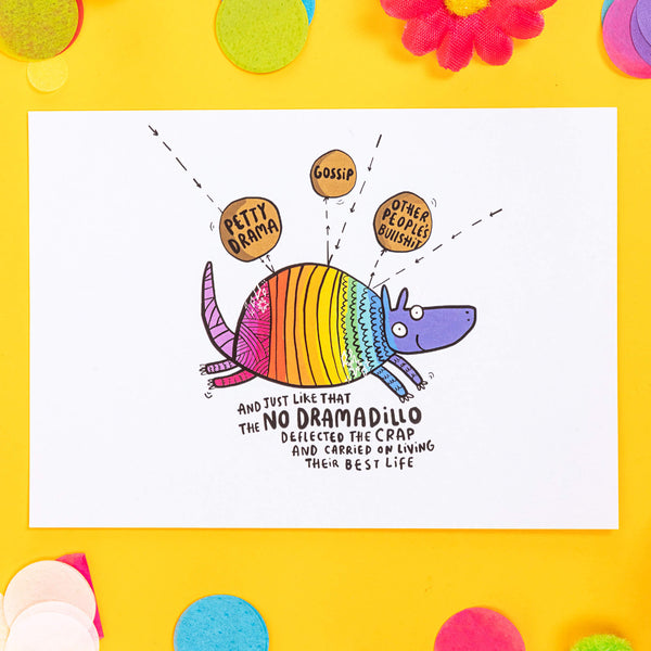 A6 Greetings Postcard featuring illustrated rainbow armadillo on light blue with black text that reads 'And just like that the no dramadillo deflected the swear word and carried on living their best life'. Designed by Katie Abey in the UK