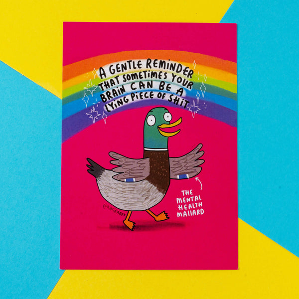 A Katie Abey greeting card depicting "The Mental Health Mallard," a cartoon duck with a rainbow background and a message that reads, "A gentle reminder that sometimes your brain can be a lying piece of shit." The card combines vibrant colours like pink and rainbow tones, promoting mental health awareness through playful and relatable humour. Katie Abey's illustrations inspire people to embrace their quirks and support mental wellbeing.