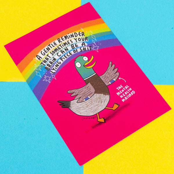 A vibrant greeting card by Katie Abey featuring a cartoon duck named "The Mental Health Mallard" with a rainbow backdrop. The text reads, "A gentle reminder that sometimes your brain can be a lying piece of shit." The design uses a mix of bold colours like pink, blue, and yellow to convey a message of mental health awareness with a humorous twist. Katie Abey, an illustrator and small business, encourages embracing your weirdness and supporting mental health.