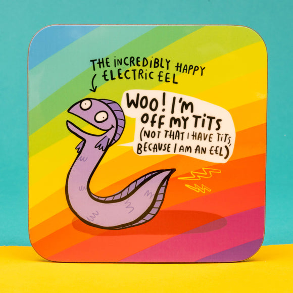Eel Coaster designed by Katie Abey in the UK. A rounded corner square coaster with a rainbow stripe background with a smiling lilac eel in the middle with a speech bubble reading 'Woo! I'm off my tits (not that I have tits because I am an eel). Near the eels tail is two yellow lightning bolts and text above with an arrow pointing at the eel reading 'The incredibly happy electric eel