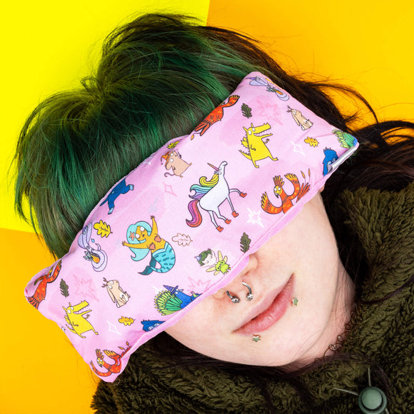 Faeryn a green haired human with facial piercings has a pink eye mask on with Katie Abey Happiness Enchanters characters on including unicorns, mermaids and dragons