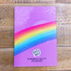 The back cover of the notebook which is purple with a rainbow going across it with Katie Abey logo.