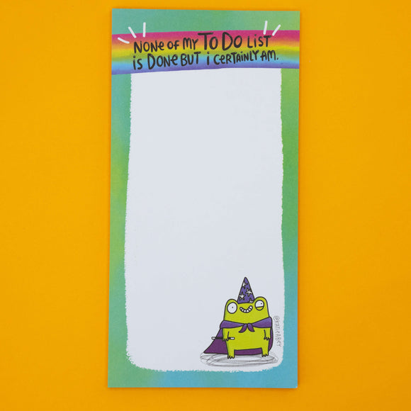 Detail of Katie Abey frog pad showing green wizard frog illustration with purple cape and starry hat. Humorous notepad design, ideal gift for stationery lovers, list makers, or anyone who enjoys playful motivational office supplies.